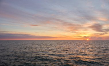 Gün batımında Baltık Denizi. Dramatik gökyüzü, mavi ve pembe parlayan bulutlar, yumuşak altın güneş ışığı, gece yarısı güneşi. Deniz manzarası, bulut manzarası, doğa. Panoramik görünüm