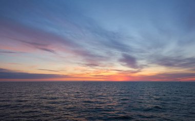Gün batımında Baltık Denizi. Dramatik gökyüzü, mavi ve pembe parlayan bulutlar, yumuşak altın güneş ışığı, gece yarısı güneşi. Alacakaranlık, yaz gecesi. Deniz manzarası, bulut manzarası, doğa. Panoramik görünüm
