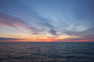 Gün batımında Baltık Denizi. Dramatik gökyüzü, mavi ve pembe parlayan bulutlar, yumuşak altın güneş ışığı, gece yarısı güneşi. Alacakaranlık, yaz gecesi. Deniz manzarası, bulut manzarası, doğa. Panoramik görünüm