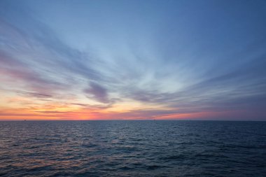 Gün batımında Baltık Denizi. Dramatik gökyüzü, mavi ve pembe parlayan bulutlar, yumuşak altın güneş ışığı, gece yarısı güneşi. Alacakaranlık, yaz gecesi. Deniz manzarası, bulut manzarası, doğa. Panoramik görünüm