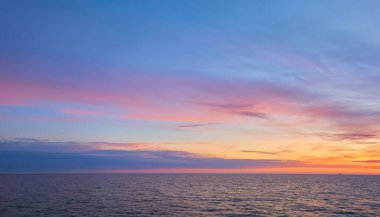Gün batımında Baltık Denizi. Dramatik gökyüzü, mavi ve pembe parlayan bulutlar, yumuşak altın güneş ışığı, gece yarısı güneşi. Alacakaranlık, yaz gecesi. Deniz manzarası, bulut manzarası, doğa. Panoramik görünüm