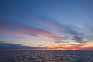 Gün batımında Baltık Denizi. Dramatik gökyüzü, mavi ve pembe parlayan bulutlar, yumuşak altın güneş ışığı, gece yarısı güneşi. Alacakaranlık, yaz gecesi. Deniz manzarası, bulut manzarası, doğa. Panoramik görünüm