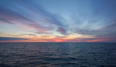 Gün batımında Baltık Denizi. Dramatik gökyüzü, mavi ve pembe parlayan bulutlar, yumuşak altın güneş ışığı, gece yarısı güneşi. Alacakaranlık, yaz gecesi. Deniz manzarası, bulut manzarası, doğa. Panoramik görünüm