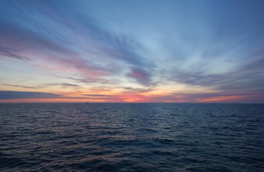 Gün batımında Baltık Denizi. Dramatik gökyüzü, mavi ve pembe parlayan bulutlar, yumuşak altın güneş ışığı, gece yarısı güneşi. Alacakaranlık, yaz gecesi. Deniz manzarası, bulut manzarası, doğa. Panoramik görünüm