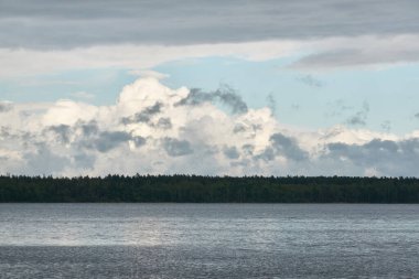 Kristal berrak bir orman gölü (nehir) kıyısından panoramik manzara. Dramatik gökyüzü, parlayan fırtına bulutları. Idyllic manzara. İlkbahar, yazın başı. Doğa, çevre, ekoloji, eko-turizm, yürüyüş
