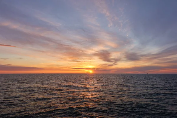 Gün batımında Baltık Denizi. Dramatik gökyüzü, mavi ve pembe parlayan bulutlar, yumuşak altın güneş ışığı, gece yarısı güneşi. Deniz manzarası, bulut manzarası, doğa. Panoramik görünüm
