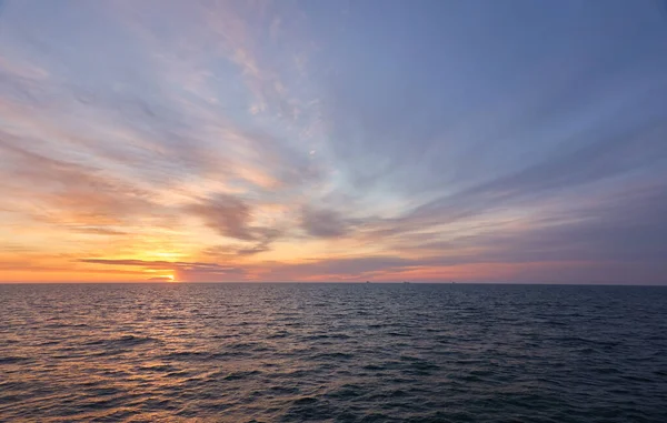 Gün batımında Baltık Denizi. Dramatik gökyüzü, mavi ve pembe parlayan bulutlar, yumuşak altın güneş ışığı, gece yarısı güneşi. Deniz manzarası, bulut manzarası, doğa. Panoramik görünüm