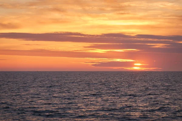 Gün batımında Baltık Denizi. Dramatik gökyüzü, mavi ve pembe parlayan bulutlar, yumuşak altın güneş ışığı, gece yarısı güneşi. Deniz manzarası, bulut manzarası, doğa. Panoramik görünüm