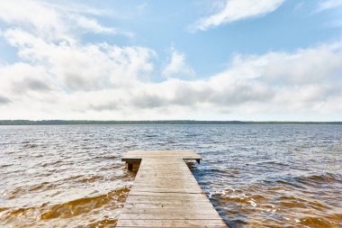 Gün batımında Busnieku Gölü. Letonya 'da sızıntı var. Ahşap iskele. Clea gökyüzü, kristal berrak suda yansıyor. Idyllic manzara, kırsal manzara. Doğa, ekoloji, eko-turizm, yürüyüş, ekolojik tatil beldesi