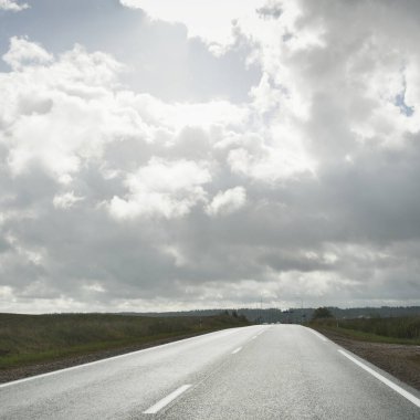 Tarlalar ve orman boyunca (asfalt yol) yol. Arabadan bak. Dramatik fırtına bulutları. Seyahat yerleri, rotalar, tatiller, lojistik, uzak yerler