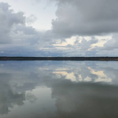 Gün batımında Orman Nehri (Lake). Dramatik gökyüzü, karanlık, parlak bulutlar. Kristal berrak suda simetri yansımaları. Panoramik sonbahar manzarası. Doğa, çevre, ekoloji, hava durumu, iklim değişikliği