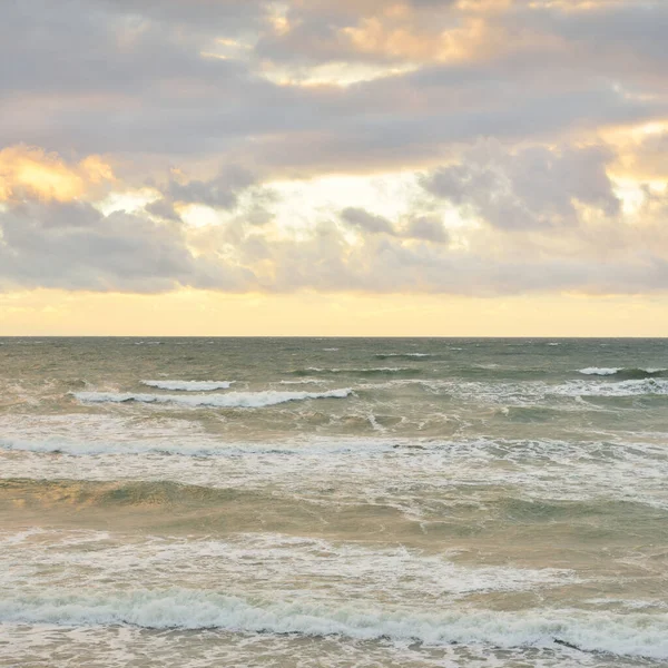 Gün batımında Baltık kıyılarından panoramik manzara. Dramatik bulutlar, parlayan bulutlar, fırtınadan sonra altın güneş ışığı. Doğa, çevre, iklim değişikliği, kararsız hava