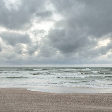 Baltık kıyıları (kum tepeleri) fırtınadan sonra gün batımında. Dramatik gökyüzü, parlayan bulutlar, rüzgar. Sonbahar manzarası. Doğa, çevre, ekoloji, kararsız hava, iklim değişikliği