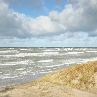 Fırtınadan sonra Baltık kıyıları (kum tepeleri, plaj). Dramatik gökyüzü, parlayan bulutlar. Resimli panoramik manzara. Doğa, çevre, ekoloji, eko-turizm, yürüyüş, keşif kavramları