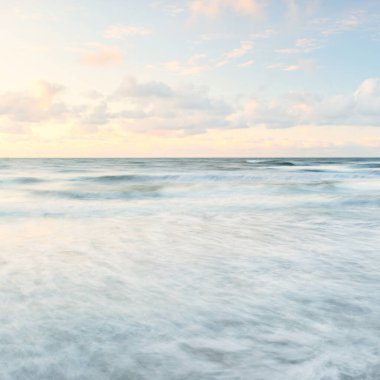 Deniz dalgaları ve sıçrama dokusu. Renkli gökyüzü suya yansıyor. Idyllic deniz manzarası. Kavramsal görüntü, uzun pozlama. Resimli bir manzara var. Arkaplan, duvar kağıdı, doğal desen, grafik kaynakları
