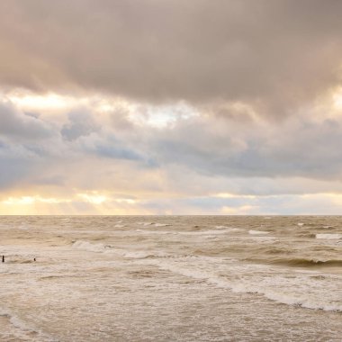 Baltic sea at sunset. Dramatic sky, blue and pink glowing clouds, golden sunlight. Waves, splashing water. Picturesque scenery, seascape, nature. Panoramic view, long exposure