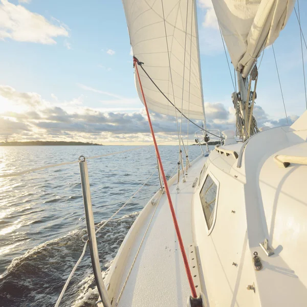 Gün batımında açık denizde yelken açmak. Güvertenin yakın görüntüsü, direk ve yelkenler. Yağmurdan sonra açık gökyüzü, çarpıcı parlayan bulutlar, altın güneş ışığı, dalgalar ve su sıçramaları, kasırga. Destansı deniz manzarası