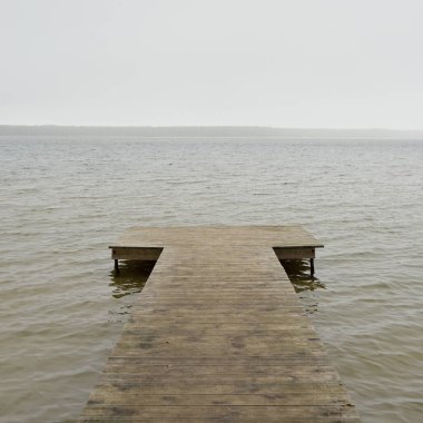 Yoğun bir siste orman nehri (göl). Ahşap iskele. Kasvetli gökyüzü, yağmur. Bulutlu bir gün. Idyllic manzara, kırsal manzara. Doğa, ekoloji, eko-turizm, yürüyüş, ekoloji beldesi, yerel turizm