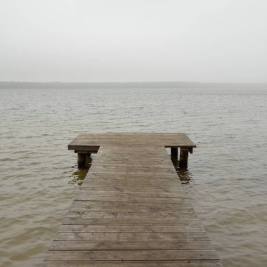Yoğun bir siste orman nehri (göl). Ahşap iskele. Kasvetli gökyüzü, yağmur. Bulutlu bir gün. Idyllic manzara, kırsal manzara. Doğa, ekoloji, eko-turizm, yürüyüş, ekoloji beldesi, yerel turizm