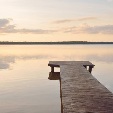 Orman Gölü (nehir) gün batımında. Ahşap iskele. Parlayan bulutlar, durgun ve berrak suda simetri yansımaları. Idyllic manzara. Doğa, ekoloji, ekolojik rezerv, eko-turizm, yürüyüş, tatiller