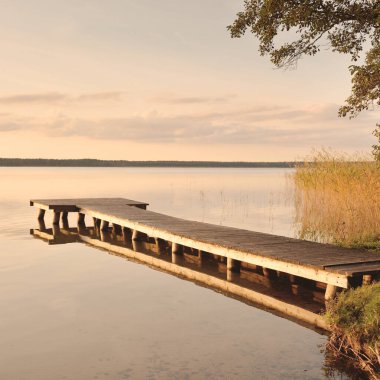 Orman Gölü (nehir) gün batımında. Ahşap iskele. Parlayan bulutlar, durgun ve berrak suda simetri yansımaları. Idyllic manzara. Doğa, ekoloji, ekolojik rezerv, eko-turizm, yürüyüş, tatiller