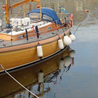 Modern klasik ahşap İsveçli yelkenli teknesi yat limanındaki bir iskeleye demirlemiş. Turizm, tatiller, boş zaman aktiviteleri, eğlence, yelkencilik temaları