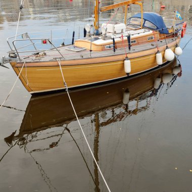 Modern klasik ahşap İsveçli yelkenli teknesi yat limanındaki bir iskeleye demirlemiş. Turizm, tatiller, boş zaman aktiviteleri, eğlence, yelkencilik temaları