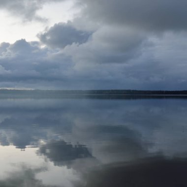 Gün batımında Orman Nehri (Lake). Dramatik gökyüzü, karanlık, parlak bulutlar. Kristal berrak suda simetri yansımaları. Panoramik sonbahar manzarası. Doğa, çevre, ekoloji, hava durumu, iklim değişikliği