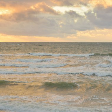 Gün batımında Baltık kıyılarından panoramik manzara. Dramatik bulutlar, parlayan bulutlar, fırtınadan sonra altın güneş ışığı. Doğa, çevre, iklim değişikliği, kararsız hava