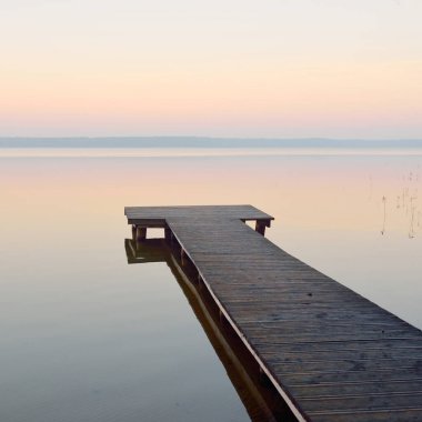 Forest lake (river) at sunrise. Wooden pier (boardwalk). Soft sunlight, mist, reflections on water. Idyllic autumn landscape. Pure nature, ecotourism, hiking, exploring