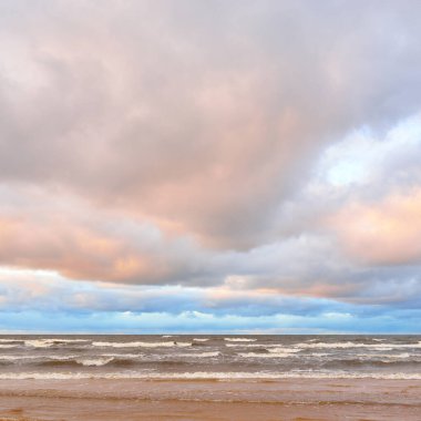 Gün batımında Baltık kıyısı. Kumsal manzarası (kum tepeleri). Dramatik günbatımı gökyüzü, parlayan bulutlar. Idyllic manzara. Doğa, tatiller, eğlence. Çevre turizmi. Panoramik görünüm