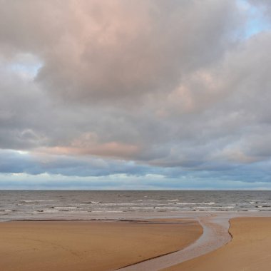 Gün batımında Baltık kıyısı. Kumsal manzarası (kum tepeleri). Dramatik günbatımı gökyüzü, parlayan bulutlar. Idyllic manzara. Doğa, tatiller, eğlence. Çevre turizmi. Panoramik görünüm