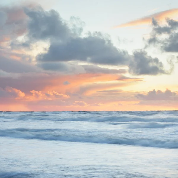 Deniz dalgaları ve sıçrama dokusu. Renkli gökyüzü suya yansıyor. Idyllic deniz manzarası. Kavramsal görüntü, uzun pozlama. Resimli bir manzara var. Arkaplan, duvar kağıdı, doğal desen, grafik kaynakları