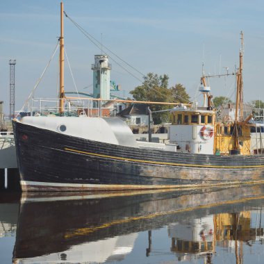 Eski bir ahşap klasik Kuzey Denizi balıkçı teknesi yat limanındaki bir rıhtıma demirlemiş. Denizcilik gemisi, ulaşım, geleneksel zanaat, sanayi