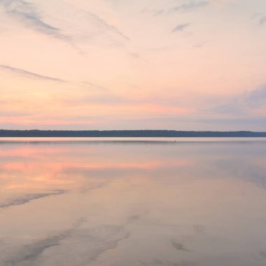 Gün batımında Orman Gölü. Yumuşak güneş ışığı, parlayan bulutlar kristal berrak suda simetri yansımaları. Idyllic manzara. Panoramik manzara. Doğa, ekoloji, çevrecilik. Barış ve neşe kavramları