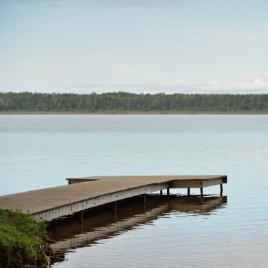 Orman nehri (göl) güneşli bir günde. Ahşap iskele. Clea gökyüzü, kristal berrak suda yansıyor. Idyllic manzara, kırsal manzara. Doğa, ekoloji, eko-turizm, yürüyüş, ekoloji beldesi, yerel turizm