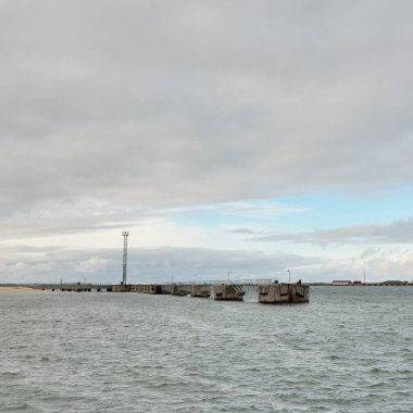 Fırtınadan sonra Baltık Denizi. Kargo iskele terminali. Dramatik bir gökyüzü. Parlayan bulutlar. Doğa, çevre, endüstri, nakliye, lojistik, küresel iletişim, ekonomi