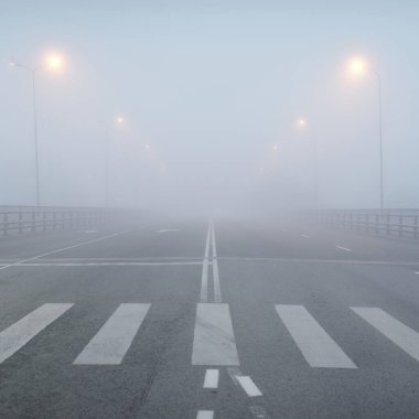 Yoğun bir siste, bomboş bir asfalt yolu (karayolu). Yaya geçidi, kavşak, sokak lambaları. Tehlikeli sürüş, yürüyüş, bisiklet, trafik kanunları