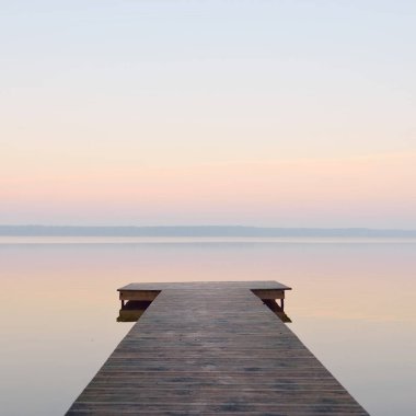 Forest lake (river) at sunrise. Wooden pier (boardwalk). Soft sunlight, mist, reflections on water. Idyllic autumn landscape. Pure nature, ecotourism, hiking, exploring