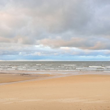 Gün batımında Baltık kıyısı. Kumsal manzarası (kum tepeleri). Dramatik günbatımı gökyüzü, parlayan bulutlar. Idyllic manzara. Doğa, tatiller, eğlence. Çevre turizmi. Panoramik görünüm