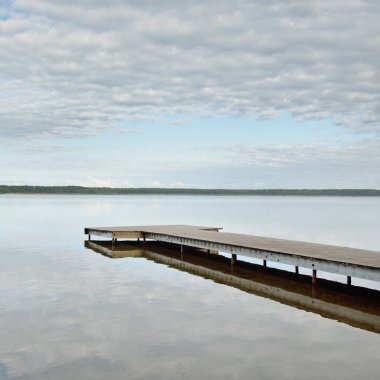 Orman nehri (göl) güneşli bir günde. Ahşap iskele. Clea gökyüzü, kristal berrak suda yansıyor. Idyllic manzara, kırsal manzara. Doğa, ekoloji, eko-turizm, yürüyüş, ekoloji beldesi, yerel turizm