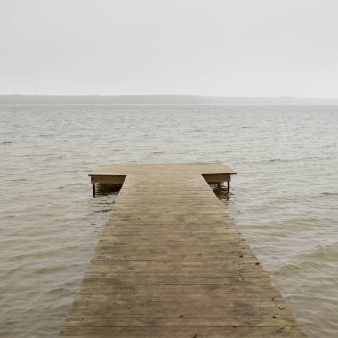 Yoğun bir siste orman nehri (göl). Ahşap iskele. Kasvetli gökyüzü, yağmur. Bulutlu bir gün. Idyllic manzara, kırsal manzara. Doğa, ekoloji, eko-turizm, yürüyüş, ekoloji beldesi, yerel turizm