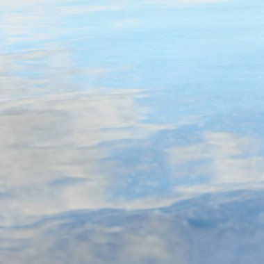 Kristal berrak suda mavi bir gökyüzünün yansımaları. Doğal doku, arka plan, grafik kaynaklar. Doğa, çevre, yaz tatilleri, plaj teması