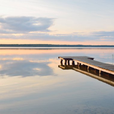 Orman Gölü (nehir) gün batımında. Ahşap iskele. Parlayan bulutlar, durgun ve berrak suda simetri yansımaları. Idyllic manzara. Doğa, ekoloji, ekolojik rezerv, eko-turizm, yürüyüş, tatiller