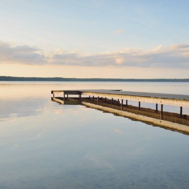 Orman Gölü (nehir) gün batımında. Ahşap iskele. Parlayan bulutlar, durgun ve berrak suda simetri yansımaları. Idyllic manzara. Doğa, ekoloji, ekolojik rezerv, eko-turizm, yürüyüş, tatiller