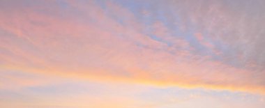 Parlayan pembe, altın rengi sirrus ve kümülüs bulutlarıyla açık mavi gökyüzü. Gün doğumu. Dramatik bulut manzarası. Sanat, meteoroloji, cennet, umut, barış, grafik kaynakları, resimli panoramik manzara