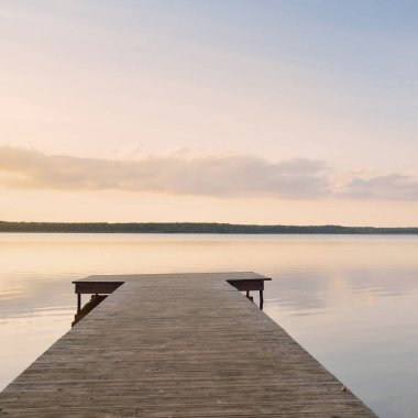 Forest lake (river) at sunset. Wooden pier. Glowing clouds, symmetry reflections in a still crystal clear water. Idyllic landscape. Nature, ecology, ecological reserve, ecotourism, hiking, vacations