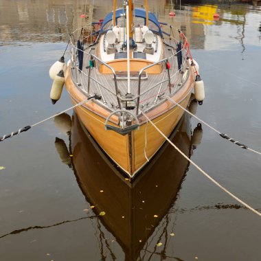 Modern klasik ahşap İsveçli yelkenli teknesi yat limanındaki bir iskeleye demirlemiş. Turizm, tatiller, boş zaman aktiviteleri, eğlence, yelkencilik temaları