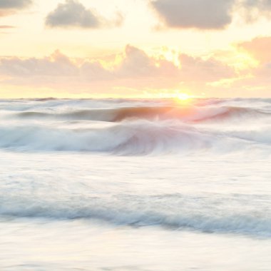 Deniz dalgaları ve sıçrama dokusu. Renkli gökyüzü suya yansıyor. Idyllic deniz manzarası. Kavramsal görüntü, uzun pozlama. Resimli bir manzara var. Arkaplan, duvar kağıdı, doğal desen, grafik kaynakları