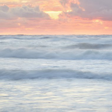 Deniz dalgaları ve sıçrama dokusu. Renkli gökyüzü suya yansıyor. Idyllic deniz manzarası. Kavramsal görüntü, uzun pozlama. Resimli bir manzara var. Arkaplan, duvar kağıdı, doğal desen, grafik kaynakları